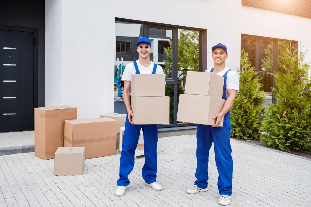 Two removal company workers are loading boxes into a minibus