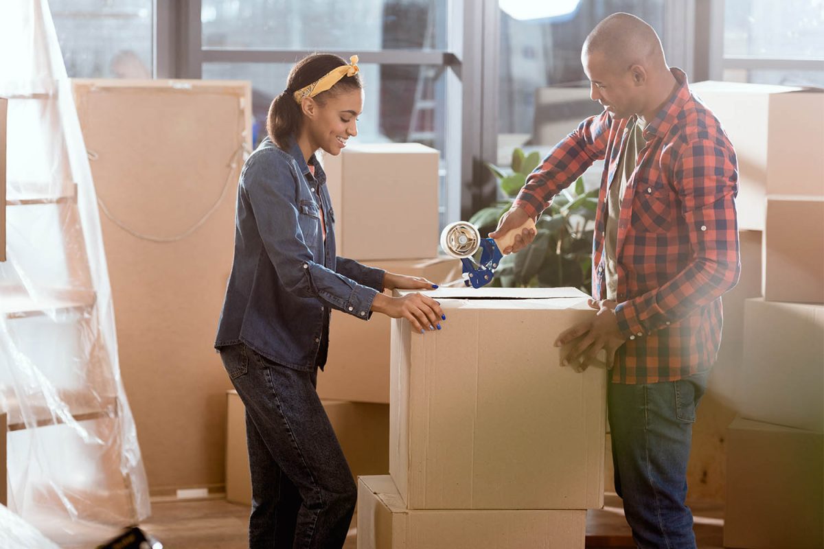 A couple receives professional assistance in moving to their new house. The teamwork of employees is evident as they unload and lift cardboard boxes during the relocation. Moving Day Concept