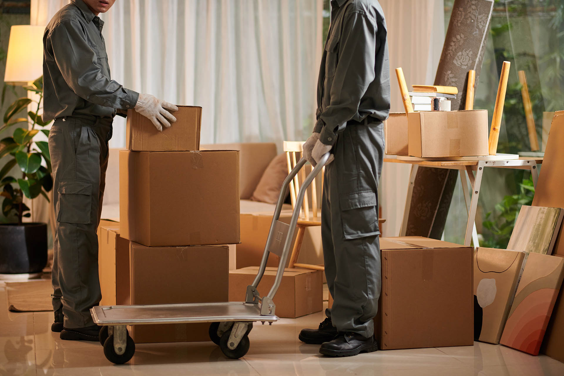 Movers putting cardboard boxes on moving cart when loading van