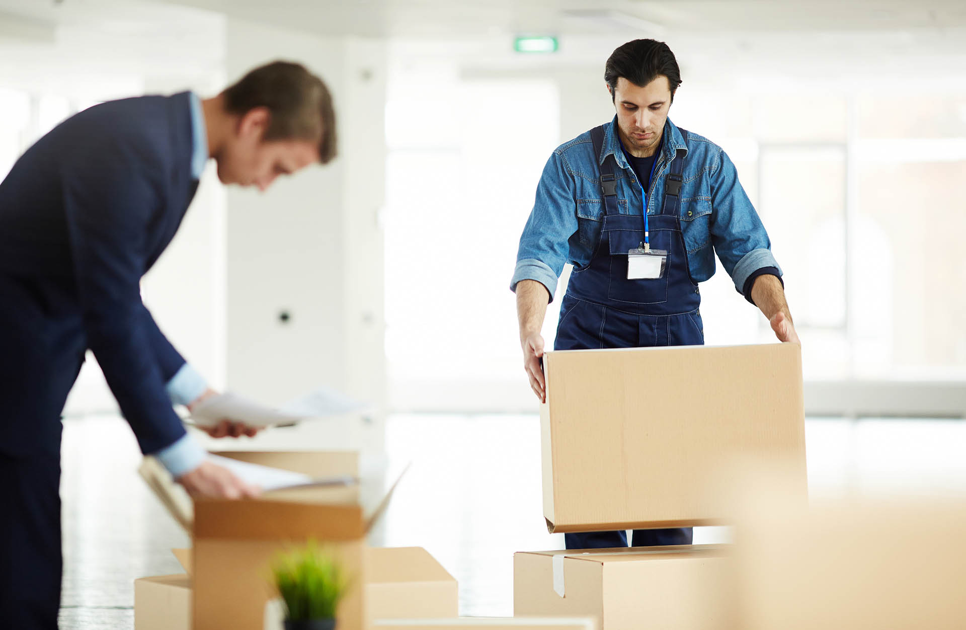 Relocation service worker putting packed box on top of another one while helping to carry packages
